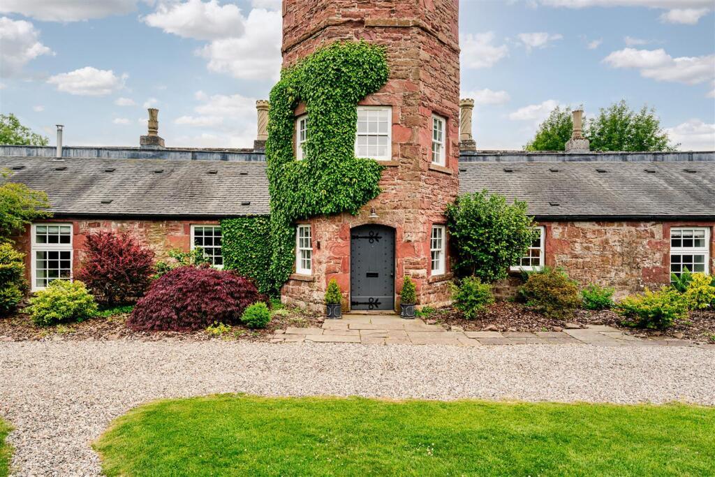 The four-storey ivy-clad folly tower with arched door, glasshouse wings either side
