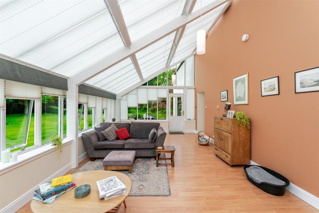 A glass-roofed sitting room with a south-facing garden outlook